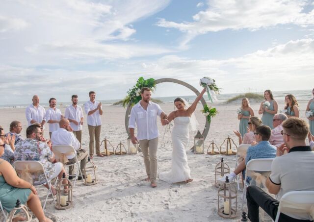A beach wedding scene with a bride and groom walking down the aisle